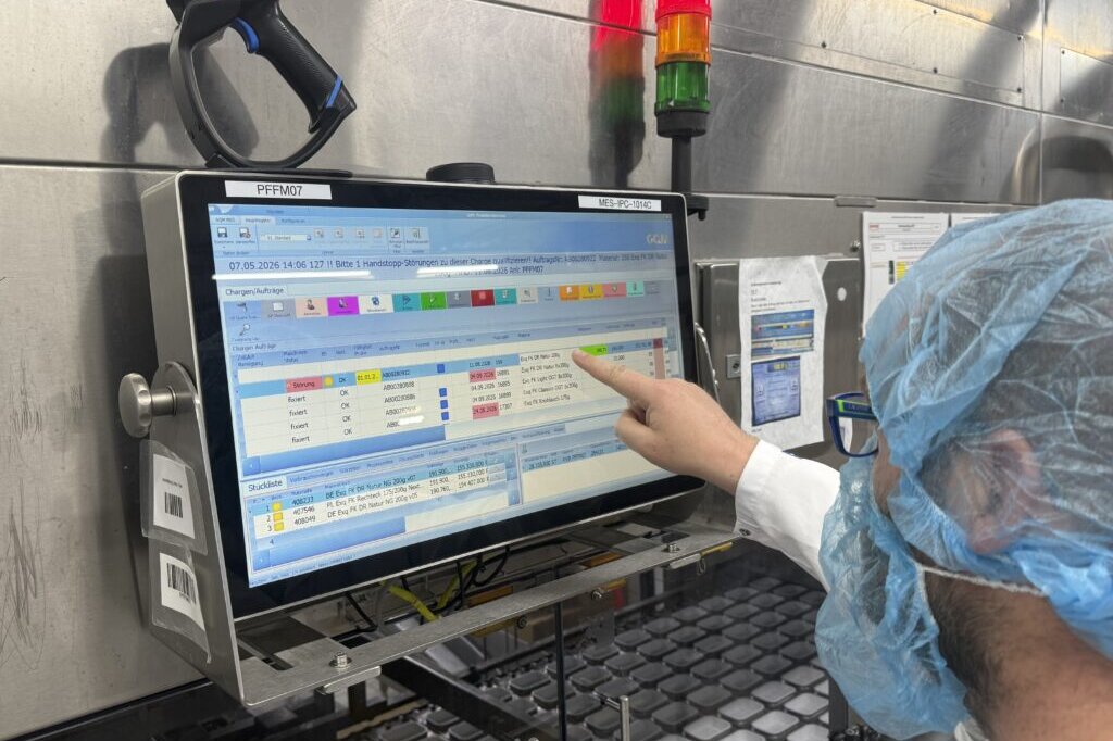 Mitarbeiter bedient die MES-Oberfläche an einem Industrie-Panel-PC in der Milchproduktion bei Karwendel.