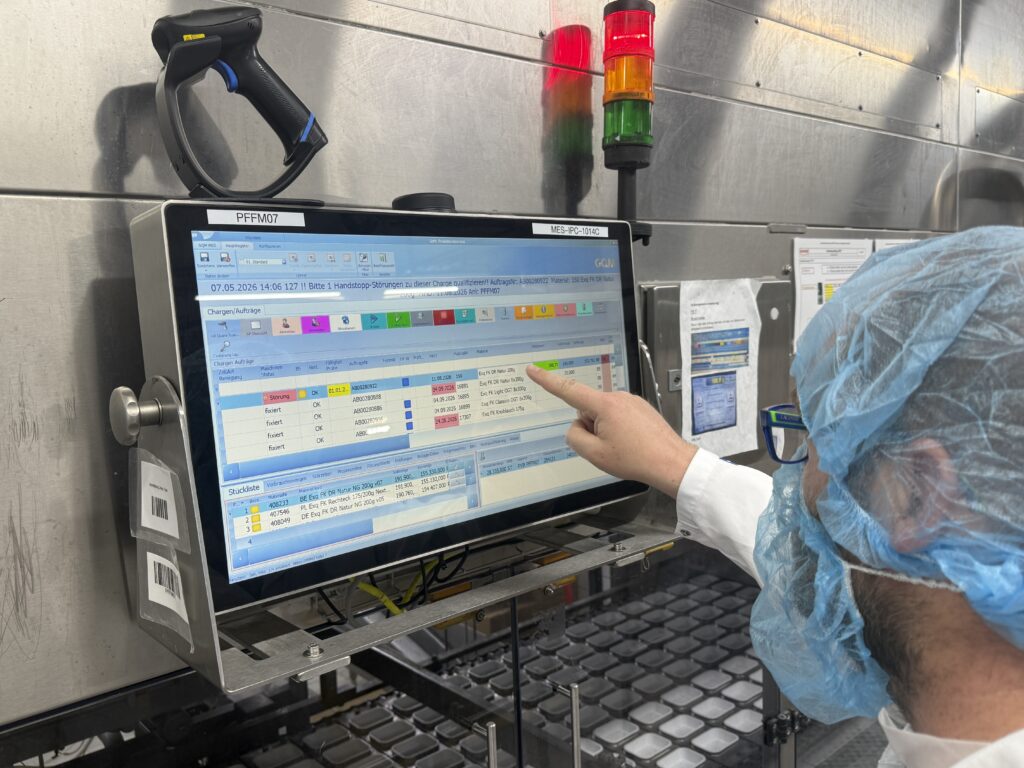 Mitarbeiter bedient die MES-Oberfl&auml;che an einem Industrie-Panel-PC in der Milchproduktion bei Karwendel.